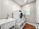 Convenient laundry room with modern washer and dryer, utility sink, and stylish white brick wall at 234 Rivercliff Dr, Stony Point, NC 28678