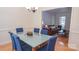 Bright dining room featuring a glass table with blue chairs and wood floors, flowing into the living room at 3008 Heathcroft Ct, Charlotte, NC 28269