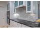 Stylish kitchen features white cabinets, mosaic backsplash, modern appliances, and dark countertops at 3008 Heathcroft Ct, Charlotte, NC 28269