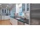 White kitchen with ample cabinet space, stainless steel appliances, and a view to the outdoors at 3008 Heathcroft Ct, Charlotte, NC 28269