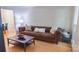 Inviting living room showcases a tufted leather sofa, wood floors, and a stylish coffee table by a bright window at 3008 Heathcroft Ct, Charlotte, NC 28269