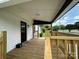 View of the front porch with wood floors and railings, black front door, and white siding at 307 W Sunset Dr, Moore, NC 28110