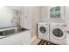 Functional laundry room equipped with a stainless-steel sink, modern white washer and dryer, and natural light at 345 Beaten Path Rd, Mooresville, NC 28117