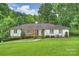 Charming single-story home with a brick and white facade, lush lawn, and mature trees providing privacy at 3504 Mountainbrook Rd, Charlotte, NC 28210
