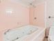 Bright pink bathroom with a white jacuzzi-style tub, tile surround, and floral wallpaper at 3985 Well Rd, Mint Hill, NC 28227