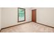 Bright bedroom with neutral carpet and trim, featuring a large window and a wood door at 3985 Well Rd, Mint Hill, NC 28227