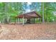 A wooden carport stands amongst trees, providing covered parking or storage space on a leaf-strewn lot at 3985 Well Rd, Mint Hill, NC 28227