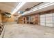Well-lit garage with wood-paneled walls, work benches, and a large garage door offering space for storage and hobbies at 3985 Well Rd, Mint Hill, NC 28227