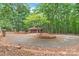 Garage surrounded by a brick garden bed and lush trees, offering shaded parking and enhanced curb appeal at 3985 Well Rd, Mint Hill, NC 28227