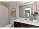 Well-lit bathroom with a dark wood vanity, white countertop, decorative mirror and a shower with a white curtain at 402 Belton St, Charlotte, NC 28209