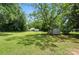 Expansive backyard featuring green grass, mature trees, and two outbuildings for storage or hobbies at 407 Rosemont Ave, Kannapolis, NC 28081