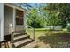 Cozy backyard entrance with brick steps, wooden railing, and views of the green, tree-filled backyard at 407 Rosemont Ave, Kannapolis, NC 28081