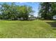 Expansive green backyard with mature trees and a storage shed, surrounding a charming home at 407 Rosemont Ave, Kannapolis, NC 28081