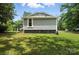 Side view of a gray home with green grass and white trim, shadowed by trees at 407 Rosemont Ave, Kannapolis, NC 28081