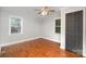 Bright bedroom showcasing wood floors, multiple windows, a ceiling fan and a closet door at 7613 Happy Hollow Dr, Mint Hill, NC 28227