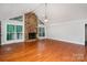 Spacious living room featuring hardwood floors, a stone fireplace, and large windows for natural light at 7613 Happy Hollow Dr, Mint Hill, NC 28227