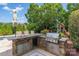 Outdoor kitchen with stone counter, built-in grill, storage, and backyard playset visible at 1032 Spyglass Ln, Waxhaw, NC 28173