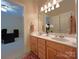 Bathroom featuring double sinks, a large mirror with lighting, and a view into an adjacent office at 11646 Hidden Forest Ln, Davidson, NC 28036