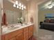 Bathroom featuring double sinks, a large mirror with lighting, and a view into an adjacent bedroom at 11646 Hidden Forest Ln, Davidson, NC 28036
