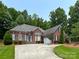 Charming brick home features a well-manicured lawn, a circular driveway, and lush landscaping at 11646 Hidden Forest Ln, Davidson, NC 28036