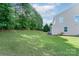 Backyard with grassy area, trees, and side view of the home at 11922 Kimberfield Rd, Matthews, NC 28105