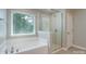 Bright bathroom with a garden tub and a separate glass shower near a window at 11922 Kimberfield Rd, Matthews, NC 28105
