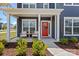 Inviting front porch with seating, a vibrant red door with wreath, and manicured landscaping at 12205 Hollinhope Dr, Charlotte, NC 28278
