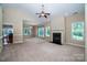 Spacious living room with a fireplace, neutral carpet, ceiling fan, and plenty of natural light at 141 Aberdeen Dr, Troutman, NC 28166