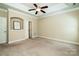 Large bedroom featuring neutral carpet, tray ceiling, niche with art and doors to bathroom and closet at 141 Aberdeen Dr, Troutman, NC 28166