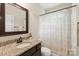 Bathroom featuring granite countertop, dark wood cabinets, and patterned shower curtain at 1830 Alden Oaks Ln, Charlotte, NC 28270