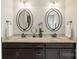 Bathroom featuring double sinks with granite counters, dark cabinets, and decorative mirrors at 1830 Alden Oaks Ln, Charlotte, NC 28270