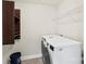 Well-lit laundry room with white appliances, shelving, and dark colored cupboard for supplies at 1830 Alden Oaks Ln, Charlotte, NC 28270