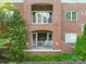 Close up of brick condo featuring dual balconies with white railings and lush greenery at 1903 Kenilworth Ave # 104A, Charlotte, NC 28203