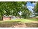 Spacious backyard with lush greenery surrounding a classic brick house with a cozy screened in porch at 1925 Montclair Ave, Gastonia, NC 28054