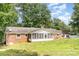 Rear view of a brick home with a screened porch, situated in a lush backyard setting at 1925 Montclair Ave, Gastonia, NC 28054
