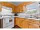 Kitchen area featuring wood cabinets, white appliances, and a double sink under a bright window at 23 Redwood Ct, Alexander, NC 28601