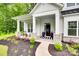 Inviting front porch with stone pillar bases, seating, and a stylish striped doormat at 2324 Loire Valley Dr, Indian Land, SC 29707