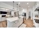Bright kitchen with white cabinets, stainless steel appliances, island with seating, and open to the living room and staircase at 2324 Loire Valley Dr, Indian Land, SC 29707
