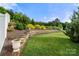 Spacious backyard with a stone retaining wall and lush landscaping at 2399 Ashbourne Se Pl, Concord, NC 28025