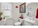 Charming half-bath features a pedestal sink, decorative mirror, and floral accents at 2399 Ashbourne Se Pl, Concord, NC 28025