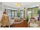 Relaxing sunroom features many windows, wicker furniture, ceiling fan, and hardwood floors at 2399 Ashbourne Se Pl, Concord, NC 28025