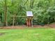 Backyard play structure with swings and a slide nestled among mature trees at 2432 Hartmill Ct, Charlotte, NC 28226