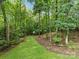 Wooded backyard with lawn and view of play structure among mature trees at 2432 Hartmill Ct, Charlotte, NC 28226