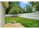 A serene backyard features a lawn, a fence, mature trees, and stone pavers at 2723 Craddock Ave, Charlotte, NC 28208