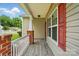 Covered porch with wood-look flooring, brick columns, and red window shutters at 2723 Craddock Ave, Charlotte, NC 28208