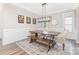 Formal dining room featuring a wooden table, wainscoting, modern light fixture and neutral decor at 2732 Berkhamstead Cir, Concord, NC 28027