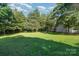 Expansive backyard featuring storage sheds, a fire pit, and mature trees at 3500 Cedar Springs Sw Dr, Concord, NC 28027