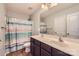 Bathroom featuring a dual sink vanity with dark wood cabinetry and a combined shower and tub with light colored shower curtain at 4151 Granite St, Midland, NC 28107