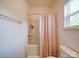 Bright bathroom featuring a shower and tub combination with a neutral peach colored shower curtain and a window at 5121 Arbordale Way, Mount Holly, NC 28120