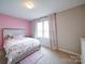 Lovely bedroom with pink accent wall, patterned bedding, and sun-filled window at 5121 Arbordale Way, Mount Holly, NC 28120